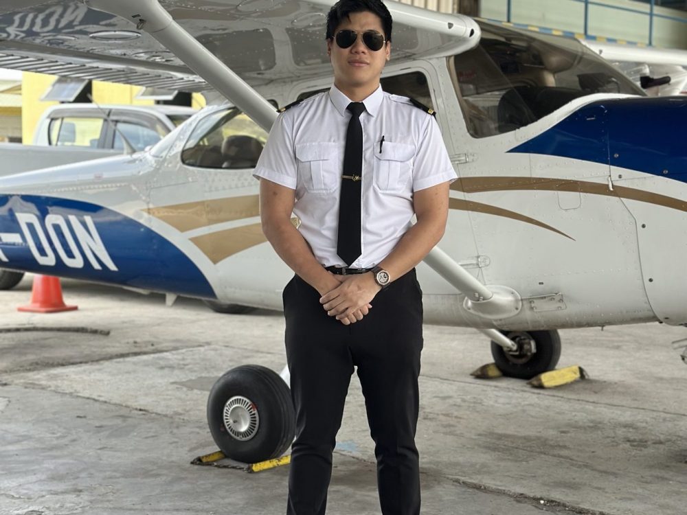 Layang Layang Flying Academy cadet in uniform beside a Cessna 172 training aeroplane