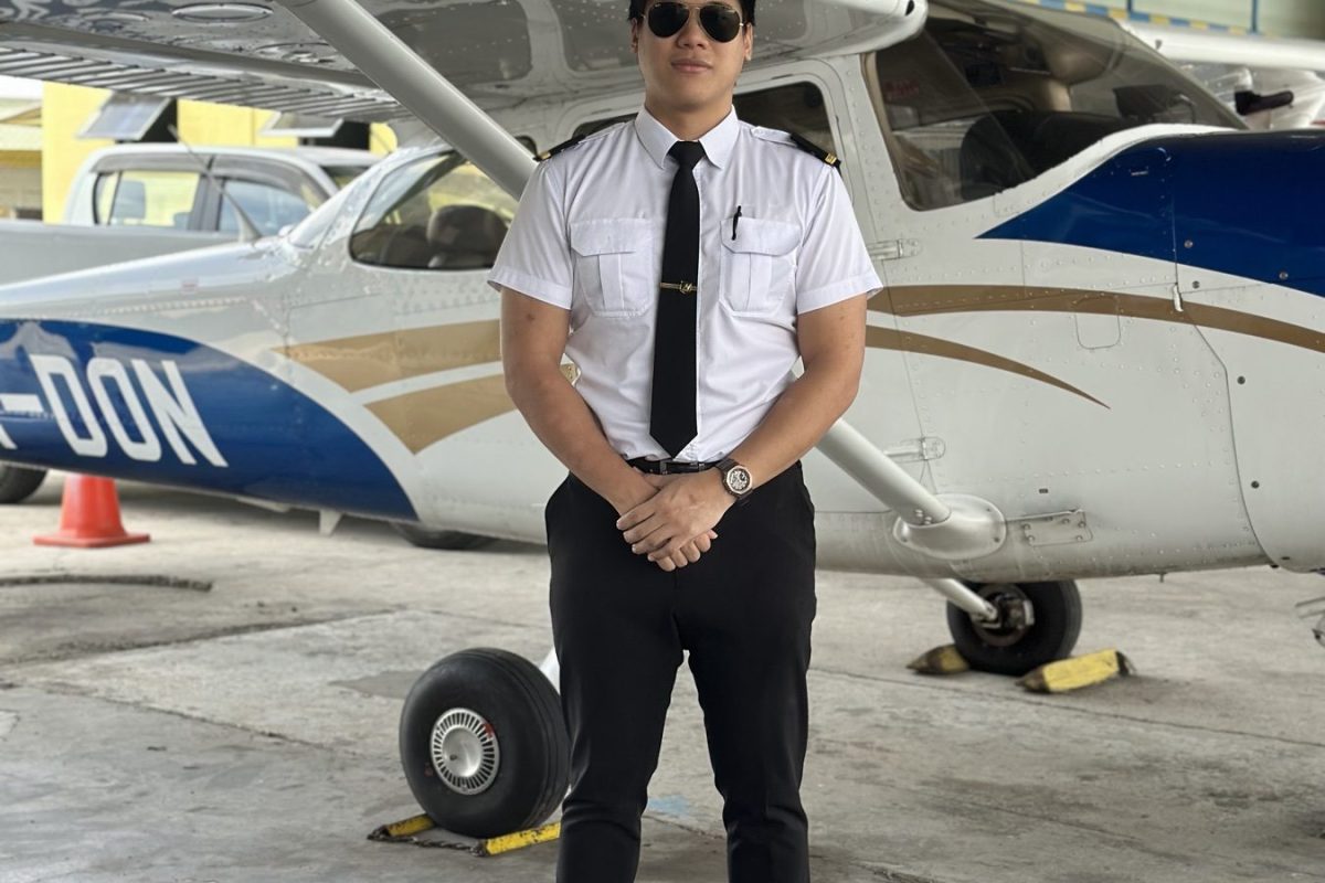 Layang Layang Flying Academy cadet in uniform beside a Cessna 172 training aeroplane